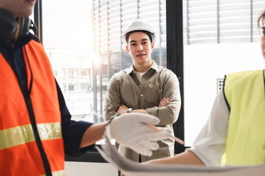 Handsome young chief engineer standing during engineer team discussion at construction site.