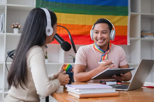 A young gay man and his girlfriend use a laptop and microphone to stream podcast audio at a studio talking about gender liberation..