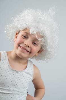 Portrait of a little Caucasian girl wearing a white curly wig on a white background