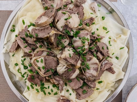 The Kazakh national dish is beshbarmak. thinly sliced beef and lamb on a large round plate with dough