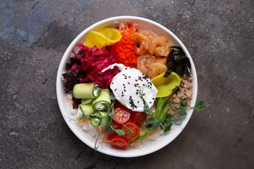 Fresh healthy food ingredients on white plate over dark background. Cucumber, carrot, shrimp, egg, cherry tomatoes, avocado, cabbage, rice.