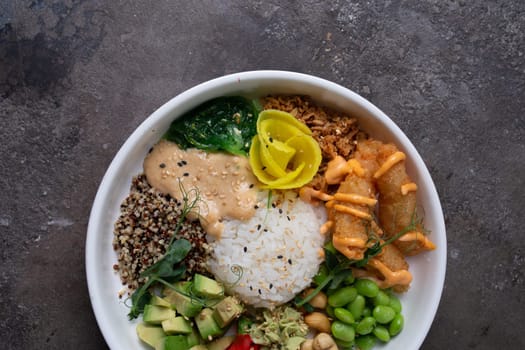 Healthy poke bowl with avocado, edamame, cucumber, carrots, salmon sesame ginger dressing. Fresh, delicious meal.