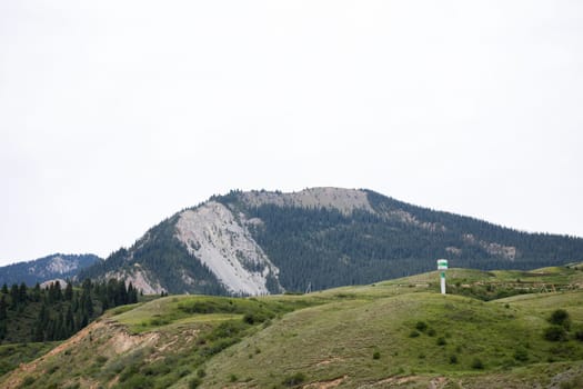 A beautiful landscape of a mountain range with a telecommunications tower on the top of the mountain in a rural area on a cloudy day.