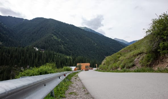 A long and winding road curves through the valley, with a house in the distance and a mountain in the background.