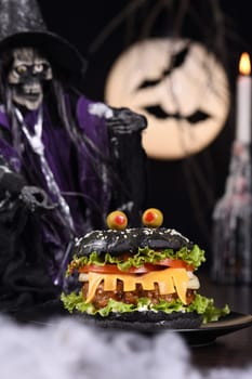 Monster Burger. Black bun, juicy beef cutlet, lettuce, onion, tomato and cheese in the shape of teeth, eyes with olives. Definitely a pick-me-up and a perfect Halloween party appetizer.