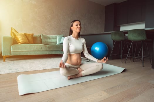 Happy young pregnant woman deep breath with fresh air doing yoga in lotus pose at home, pregnancy with yoga and meditation for healthy life, motherhood and healthy pregnancy concept. High quality photo