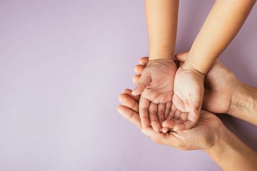 Top view of parents and kid holding empty hands together on a color background. Family day celebrating togetherness and support.