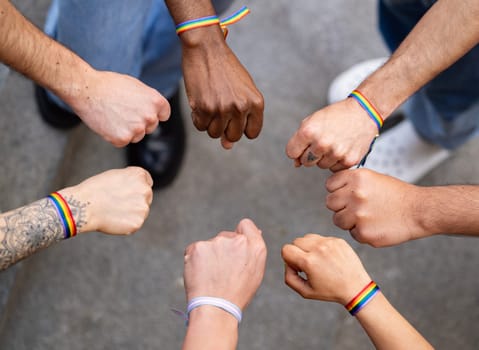 Fists or closed hands of multiethnic homosexual group of people showing unity with rainbow bracelets.