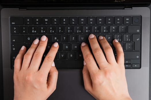 BERLIN, GERMANY - APRIL 14 2024: Woman hands on the keyboard of MacBook Pro, top view