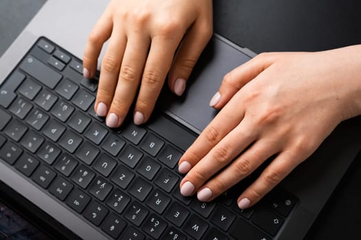 BERLIN, GERMANY - APRIL 14 2024: Womans hands typing on laptop keyboard, top view.