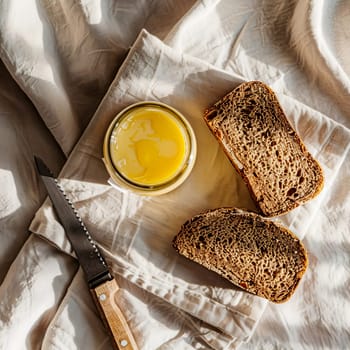 Top view of a jar of ghee and two slices of healthy whole grain bread on a light background. Healthy diet.