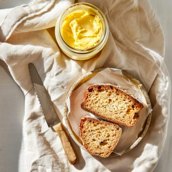 Top view of a jar of ghee and two slices of healthy whole grain bread on a light background. Healthy diet.