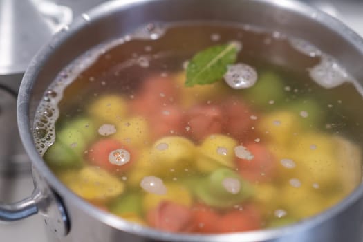 In a pot, colorful dumplings are being boiled. Preparing lunch or dinner for children and family.