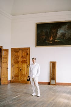 Young male photographer with a camera stands in the large hall of an ancient villa. High quality photo