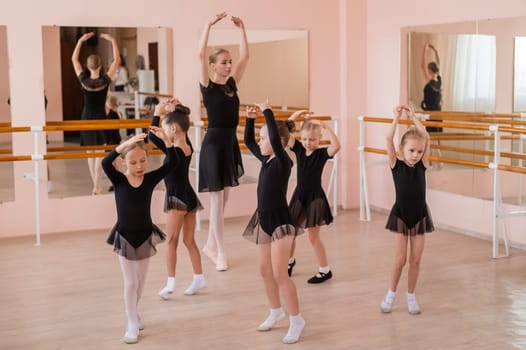 Children's ballet school. Caucasian woman teaching ballet to little girls