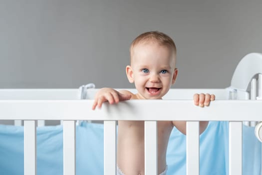 Laughing baby reaching out from his crib.