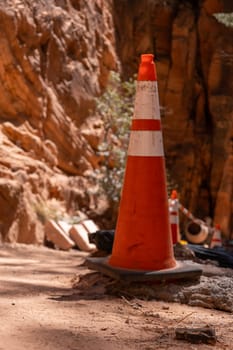 Orange caution cone on Zion red sandstone cliffs park trail construction. Cement mixer. Selective focus high quality photo