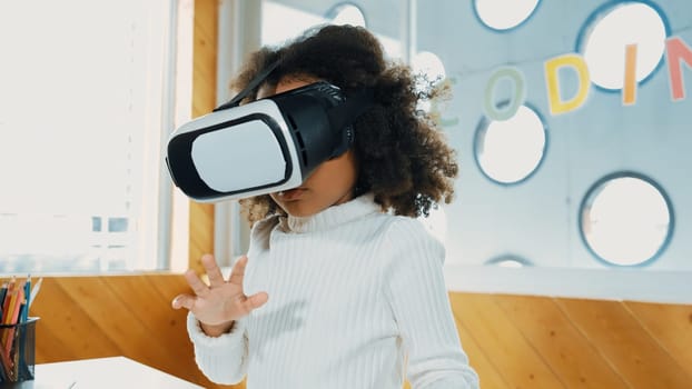 Creative girl wearing VR headset to learning in metaverse. Funny kid enjoy to wearing AI headset and enter to virtual world program in STEM technology class. Innovation. Future lifestyle. Erudition.