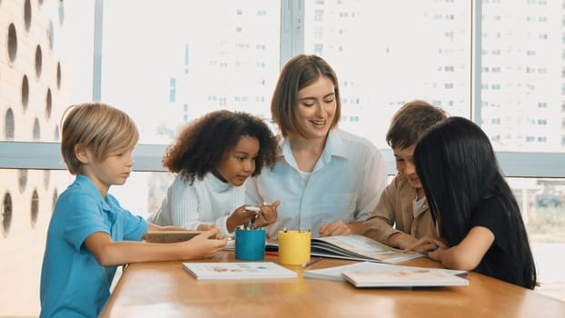 Happy diverse student and smart teacher drawing and coloring by using marker at drawing book. Multicultural smart learner using drawing book while talking to skilled caucasian instructor. Erudition.