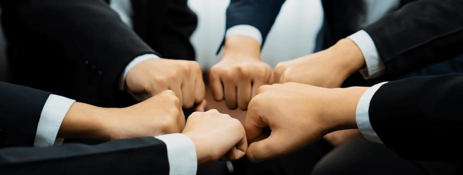 Office worker team stacking hand together symbolize successful group of business partnership and strong collective unity teamwork in community workplace in panoramic banner. Shrewd