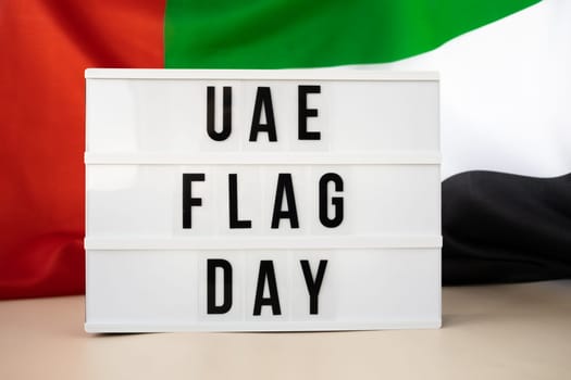 Lightbox with text UAE FLAG DAY on United Arab Emirates waving flag made from silk material. Independence Commemoration Day Muslim Public holiday celebration background. The National Flag of UAE. Patriotism