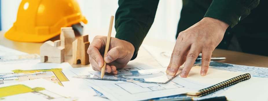 Professional engineer measuring the blueprint. Professional engineer working architectural project at studio on a table with yellow helmet and architectural equipment scatter around. Delineation.