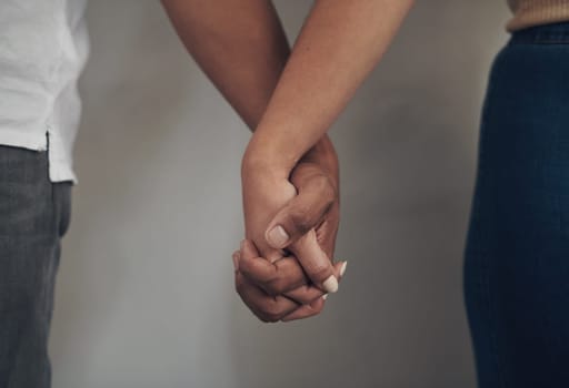 Couple, love and holding hands for support, care and solidarity or romance with studio background. Compassion, partnership or relationship for people, marriage or hope or trust for affection together.