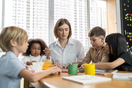 Teacher is teaching student about lesson from the books in the classroom, the children are happy. Some ask teacher, a boy in blue shirt is reading a book on his own and a girl is drawing. Erudition.