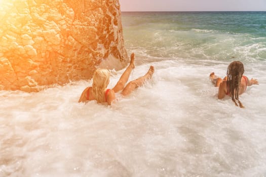 Women ocean play. Seaside, beach daytime, enjoying beach fun. Two women in red swimsuits enjoying themselves in the ocean waves