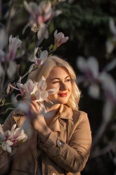 A woman is holding a magnolia flower in her hand and standing in front of a tree. Concept of serenity and beauty, as the woman is surrounded by nature and the flower adds a touch of color