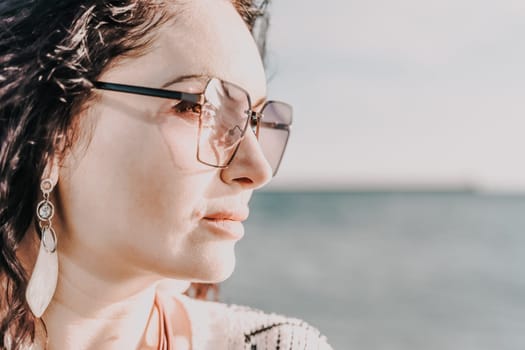 Portrait of a curly woman in glasses on the background of the sea. Vacation on the sea, walk, tourism