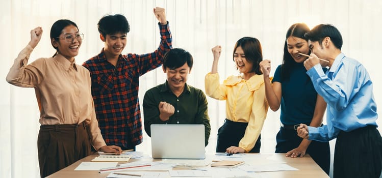 Happy professional business team celebrate their success project at modern meeting room on table with business document scattered. Manager and coworker happy because of increasing sales. Delineation.