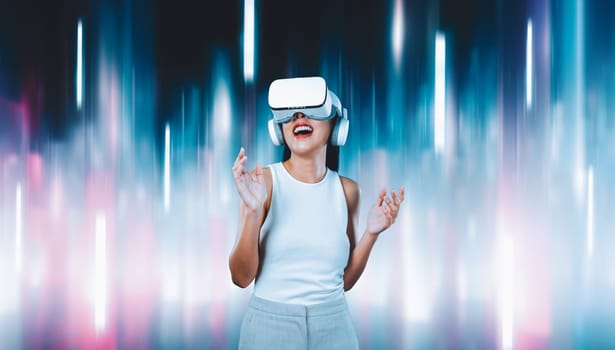 Female standing and wearing white VR headset and white sleeveless connect metaverse, future technology creating cyberspace community. She enjoy look fantasy abstract light around her. Hallucination.