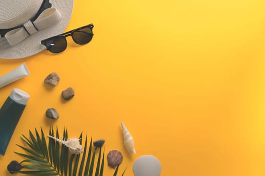 Summer holiday concept. Top view sunglasses, straw hat and seashells on yellow background.