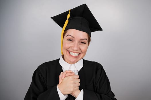 Caucasian woman in graduate gown dreamily holds her hands on her chest