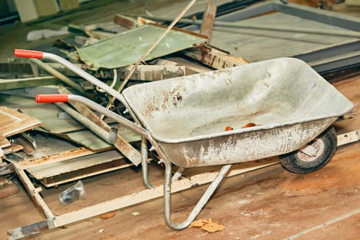 a small cart with a single wheel at the front and two supporting legs and two handles at the rear