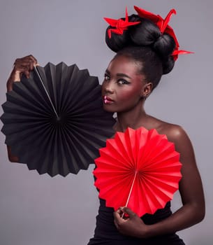 Black woman, fashion and studio for African portrait, oriental paper art and origami with fan or cosmetic beauty. Makeup, swan inspiration and trendy with cosmetology, culture or tradition with pride.