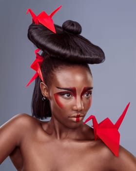 Traditional, makeup and origami with black woman in studio for creative, cosmetics and asian aesthetic. Beauty, paper design and model for heritage, art and confidence on gray background.