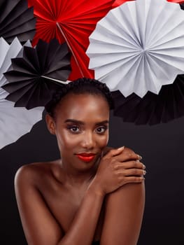 Beauty, portrait and black woman with origami fans in studio, smile and dark background. Face, makeup and cosmetics of female model for aesthetic, traditional Japanese and paper art for culture hat.