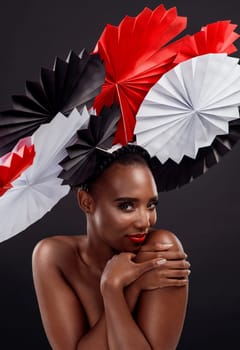 Black woman, portrait and smile with origami fans in studio isolated on a dark background. Face, makeup cosmetics and skincare of female model with beauty and traditional paper art for geisha hat.