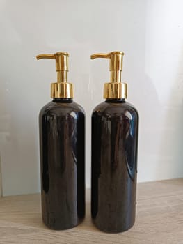 Black plastic bottle soap cleaning dish washer dispenser staying on the kitchen wooden table. High quality photo.