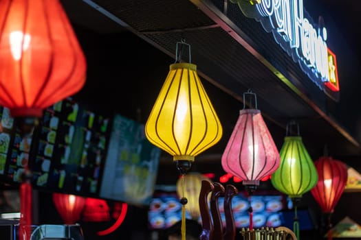 The restaurant is adorned with a row of colorful lanterns hanging from the ceiling, creating a vibrant atmosphere in the room
