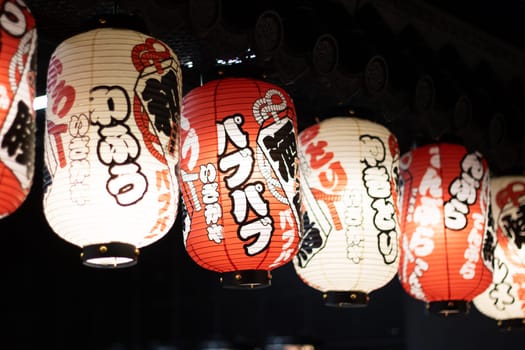 The restaurant is adorned with a row of colorful lanterns hanging from the ceiling, creating a vibrant atmosphere in the room