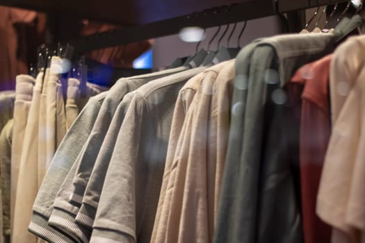 A row of Fashion design shirts, including Denim and Sportswear in Electric blue, are hanging on Clothes hangers in a Retail store