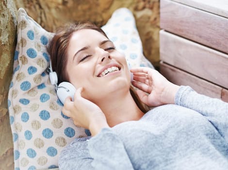 Cheerful, woman and headphones and listening with music, podcast or audio on couch in backyard. Female person, smile and happy at home in outdoor in relax, free and peace with tech for streaming.