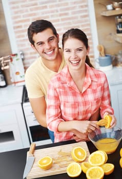 Couple, kitchen and smile with orange for juice in bowl for health, nutrition and diet with ingredients. Home, relationship and bonding with fruit for sweet flavor, lunch snack and fresh in portrait.