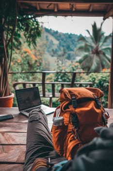 Close-up of a traveler's legs with a laptop on a wooden balcony, overlooking a lush jungle setting