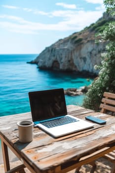 Laptop set up on a wooden table with a breathtaking view of the sea and cliffside