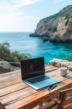 Laptop set up on a wooden table with a breathtaking view of the sea and cliffside