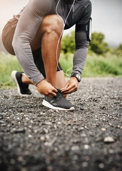 Person, hands and shoelace with fitness or running for exercise, health and wellbeing in outdoor. Road, sneakers and committed on workout or jog in morning for training, wellness and self care.